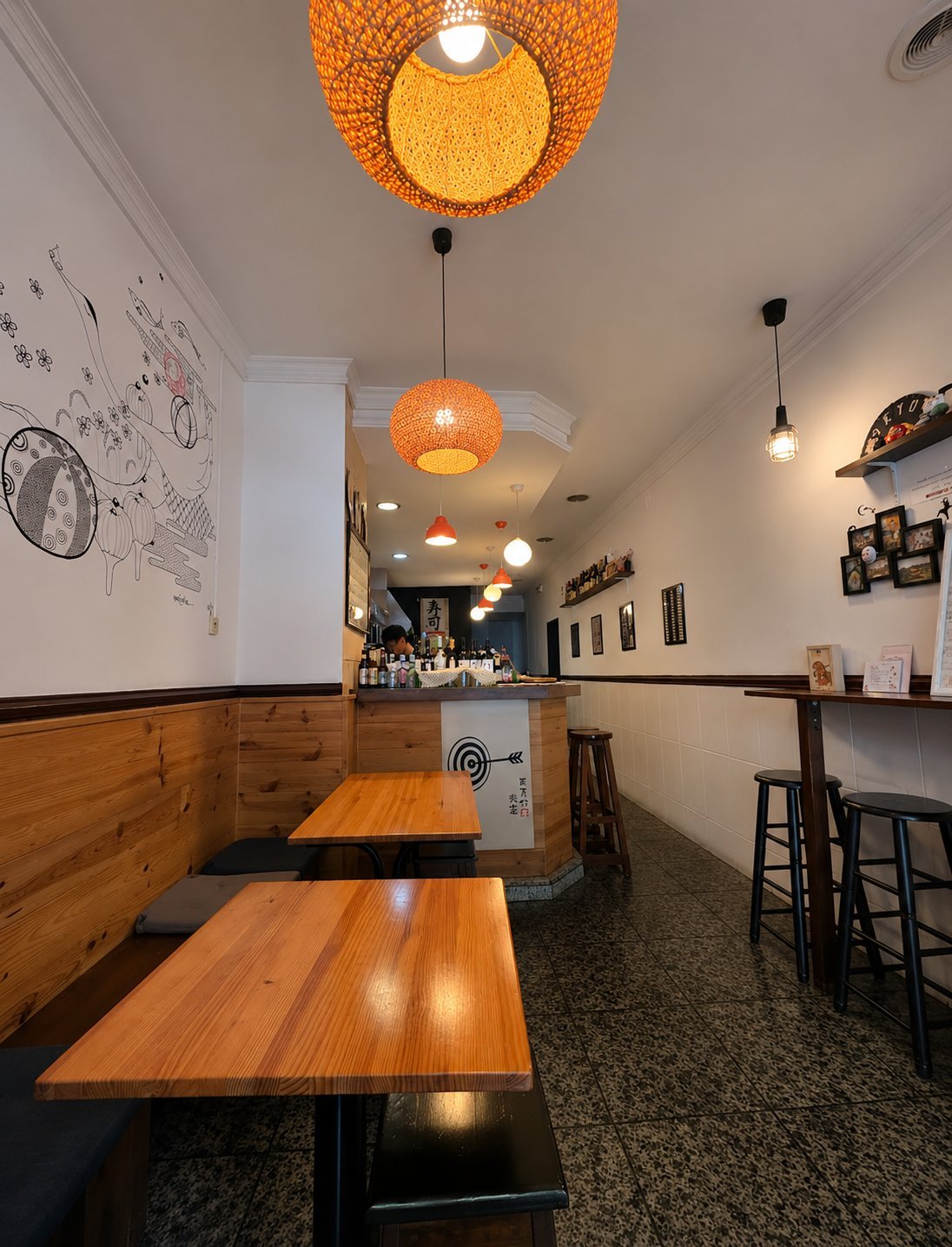 Interior de Maruya まるや食堂 — sólo dos mesas de madera, lámparas tejidas y barra de sushi